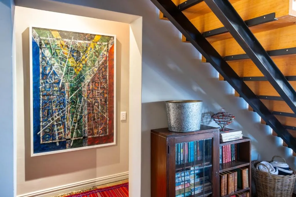 Interior staircase with colorful abstract map artwork and wooden shelving displaying books and decor