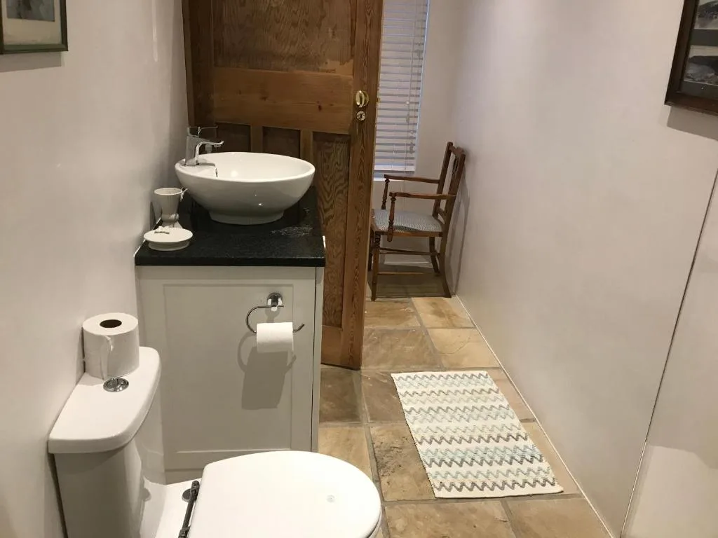 Modern bathroom with round sink, toilet, and stone tile flooring