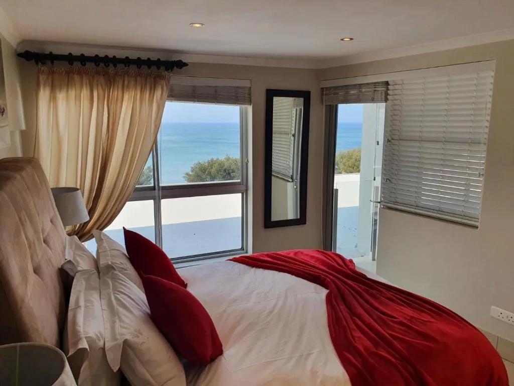 Spacious bedroom with ocean views through multiple windows and glass doors