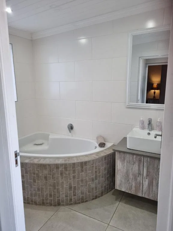 Modern bathroom with corner bathtub and white tile walls