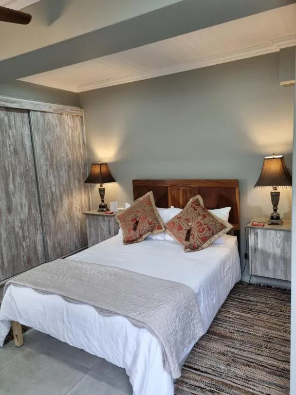 Bright bedroom with queen bed, decorative pillows, wooden headboard, bedside lamps