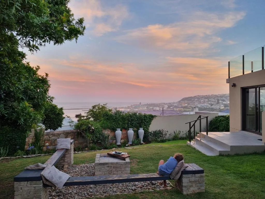 Outdoor garden seating area with lagoon and coastal town views at sunset