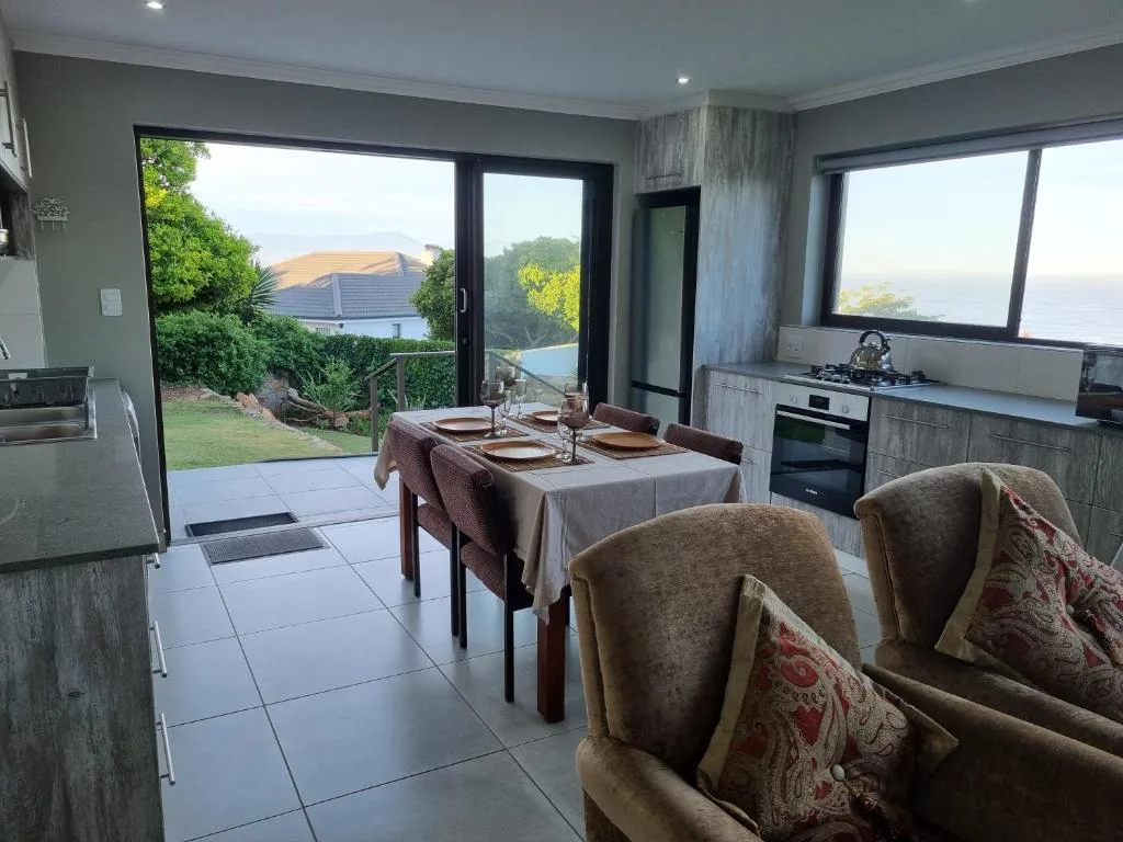 Open-plan dining area with set table, ocean views through large windows