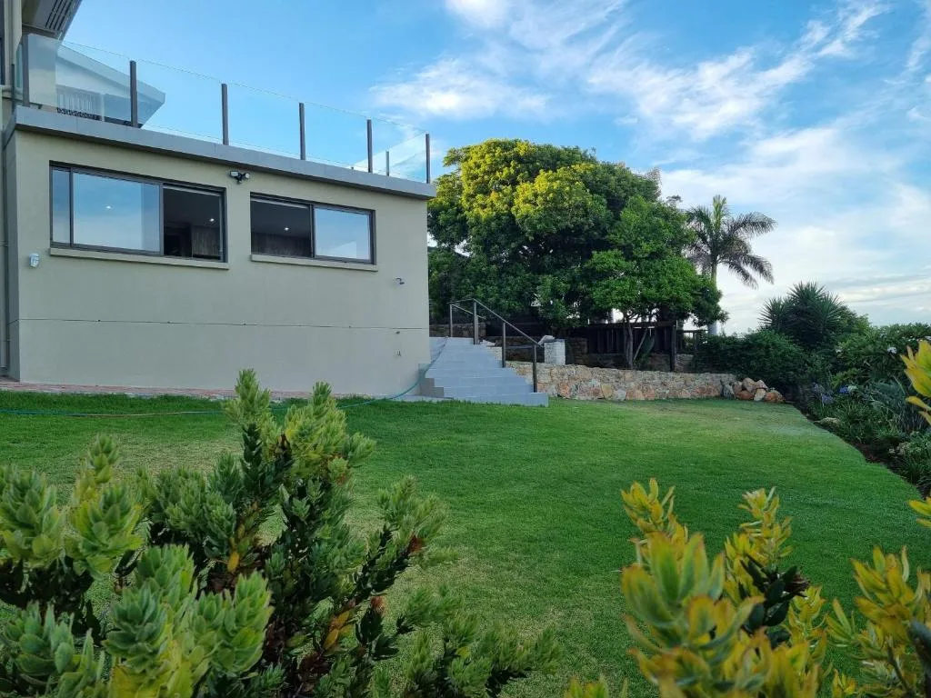Modern white apartment building with manicured gardens and mature trees
