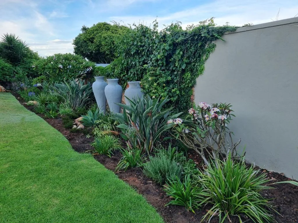 Manicured garden with decorative blue urns, flowering plants, and green lawn