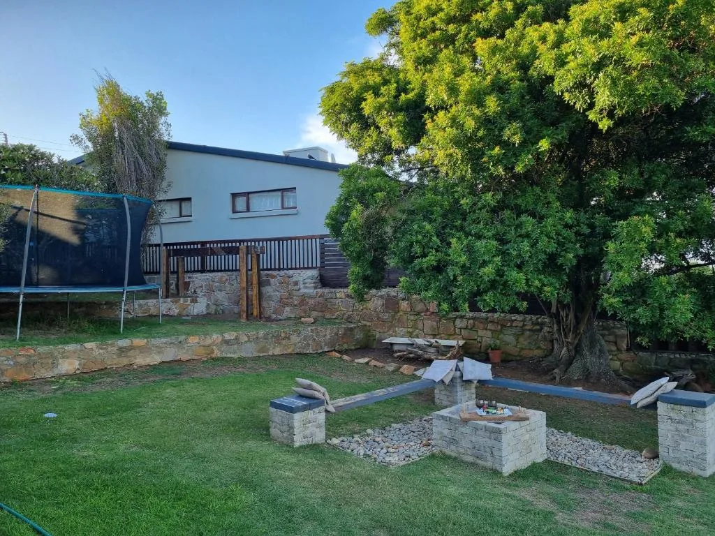 Modern white holiday home with stone base and manicured garden grounds