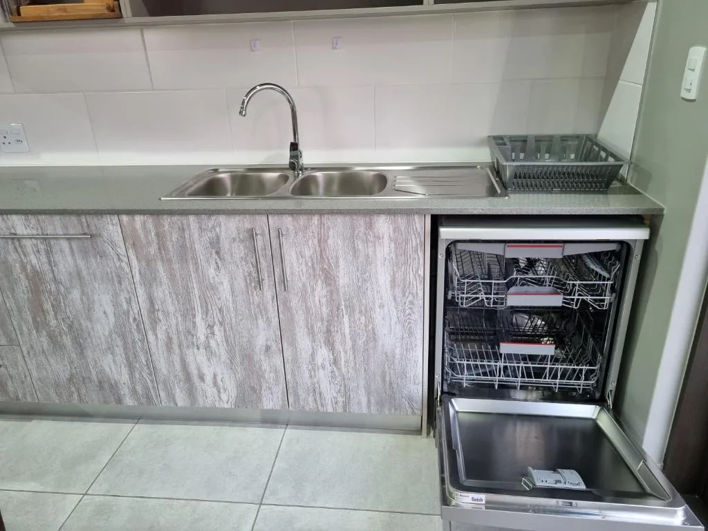 Modern kitchen with stainless steel sink, dishwasher, and wood-grain cabinetry
