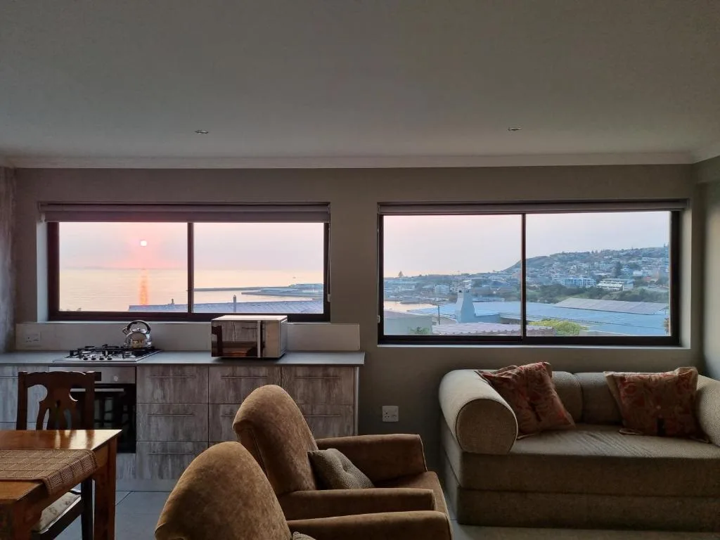 Living room with comfortable seating and panoramic ocean and coastal town views through large windows