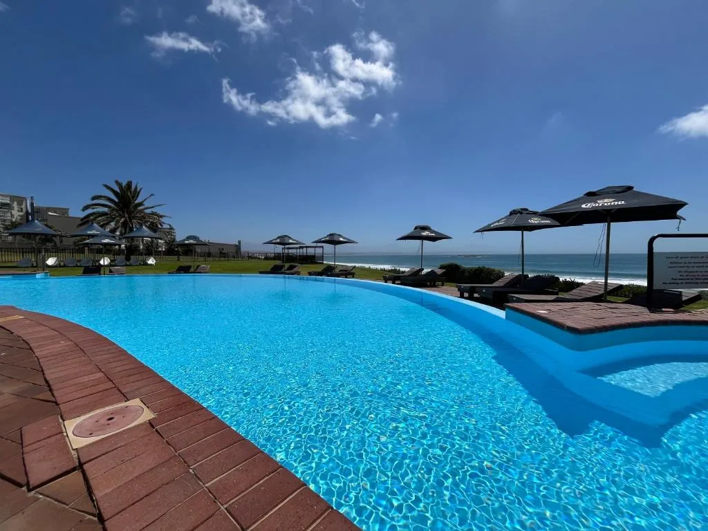Large resort swimming pool with ocean view and black umbrellas