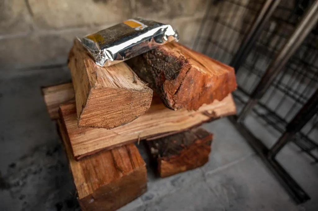 Close-up of rustic wooden logs with silver lighter on outdoor surface