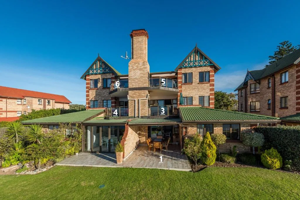 Victorian brick building with green roof and manicured lawn gardens