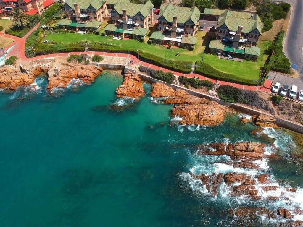 Turquoise ocean waters and rocky coastline with seaside property buildings