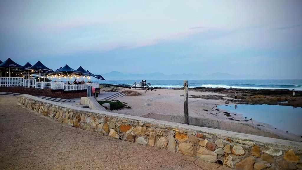 Twilight beach view with beachfront restaurant pavilions and ocean horizon