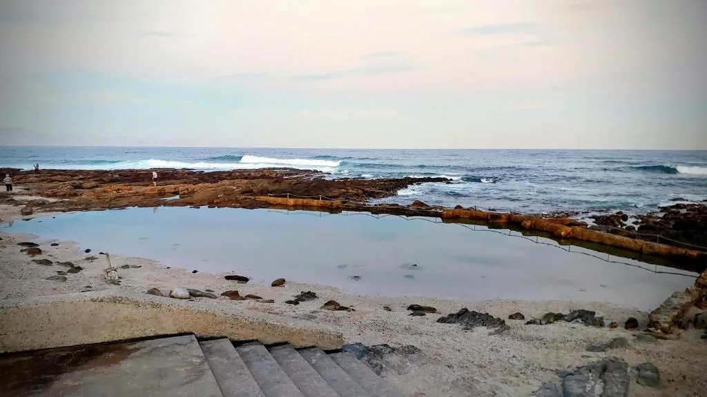 Coastal tidal pool with ocean waves and rocky shoreline beyond
