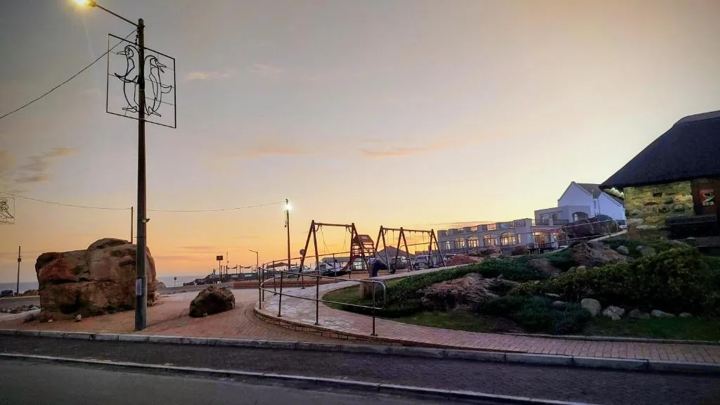 Sunset over coastal town with historic buildings and playground area