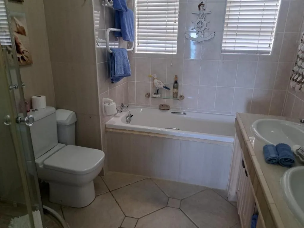 Bright bathroom with toilet, bathtub, sink vanity, and tiled flooring