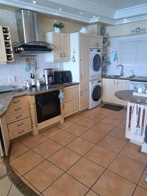 Spacious kitchen with wooden cabinetry, black stove, stainless steel appliances, and washer-dryer