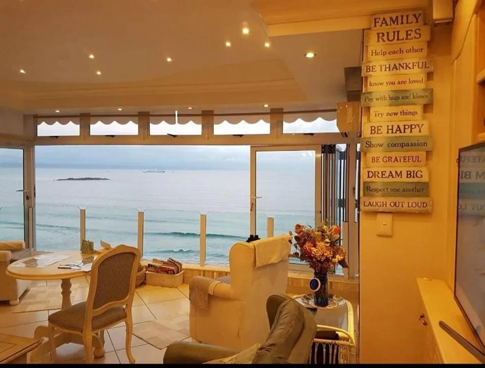 Sunny lounge with ocean views through floor-to-ceiling windows and deck access