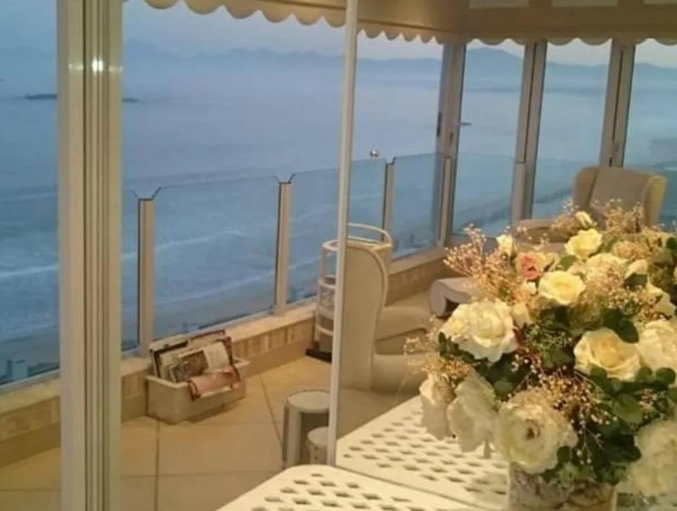 Panoramic ocean view through floor-to-ceiling windows with fresh flowers