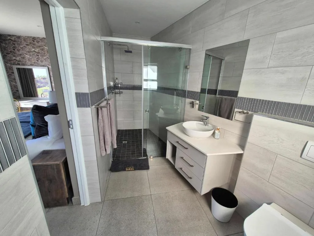 Modern bathroom with walk-in shower, white vanity, and light wood tiling