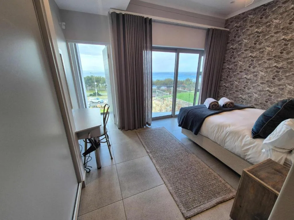 Spacious bedroom with sea view, modern furnishings and glass doors