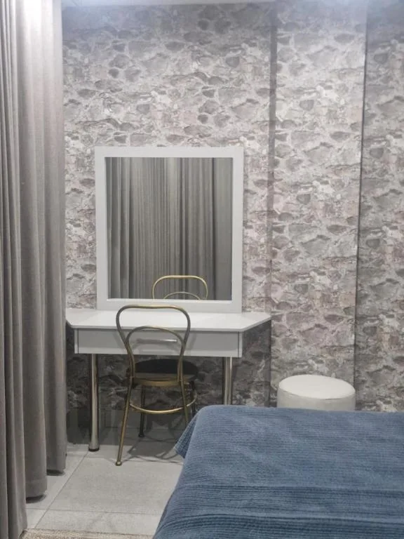 Modern bedroom with vanity desk, mirror, and blue bedding visible