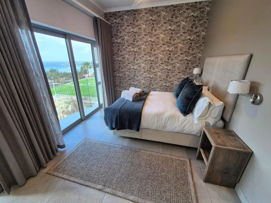 Modern bedroom with ocean view through large sliding glass doors and balcony