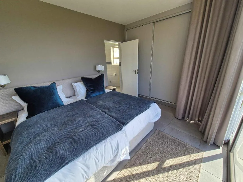 Modern bedroom with twin beds, blue cushions, and built-in wardrobe