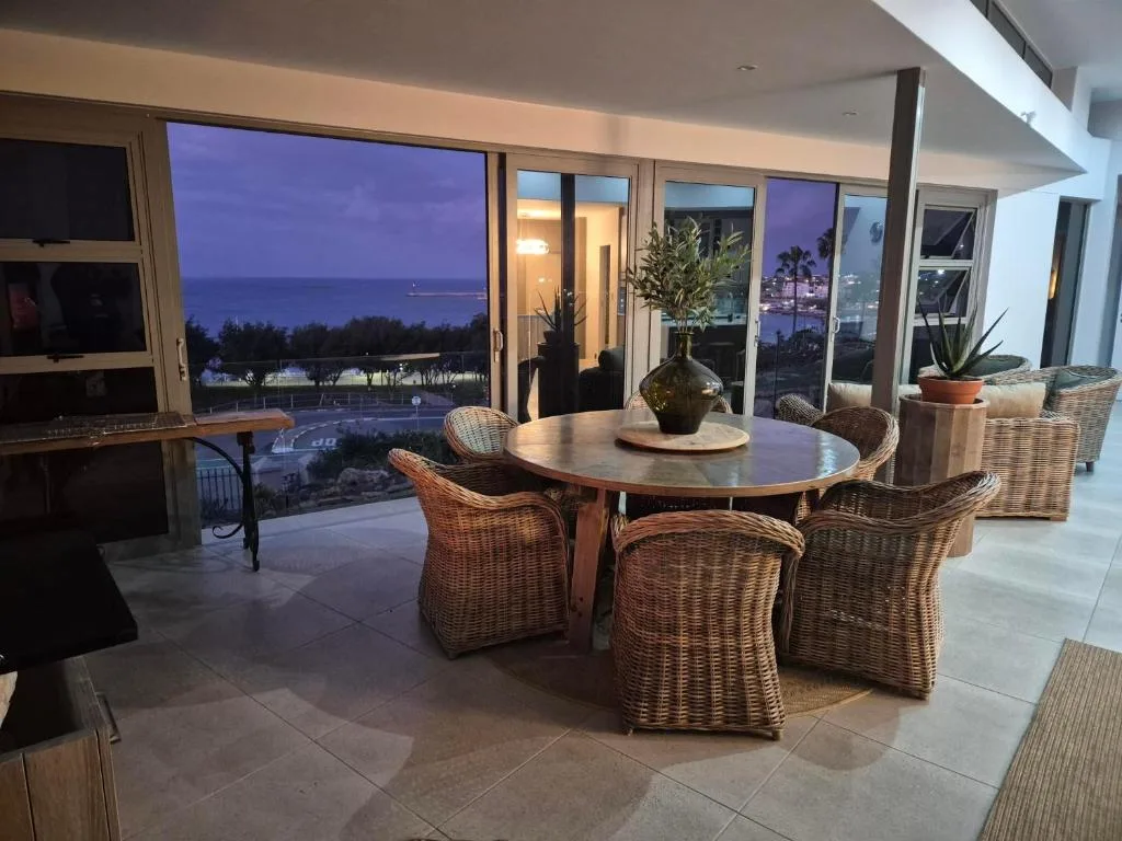 Spacious outdoor deck with round dining table and ocean view at dusk