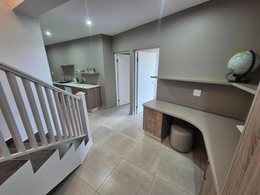 Modern mezzanine space with desk, kitchenette, and staircase railing
