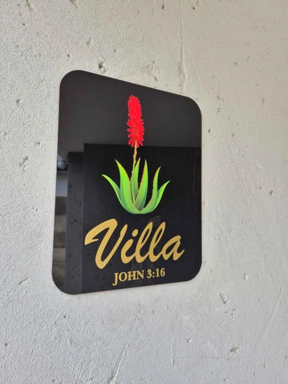 Casa de Santos villa entrance sign with red flower logo on white wall
