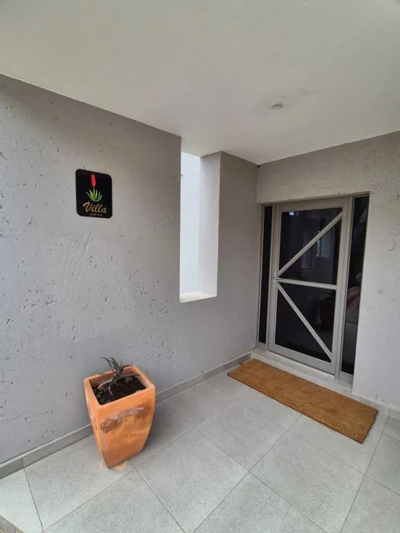 Modern entrance with tiled floor, potted plant, and glass door