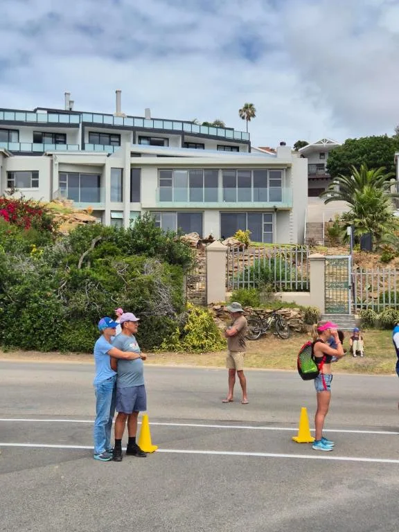 Modern white villa with large windows and manicured gardens facing street