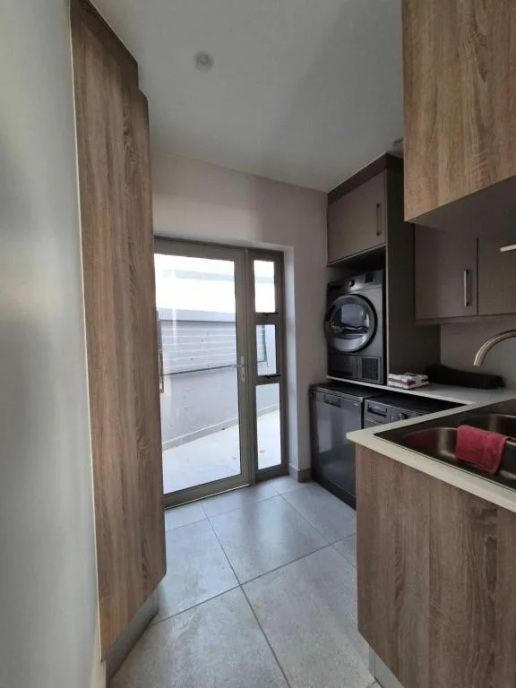 Modern kitchen with black appliances and wood cabinetry overlooking ocean
