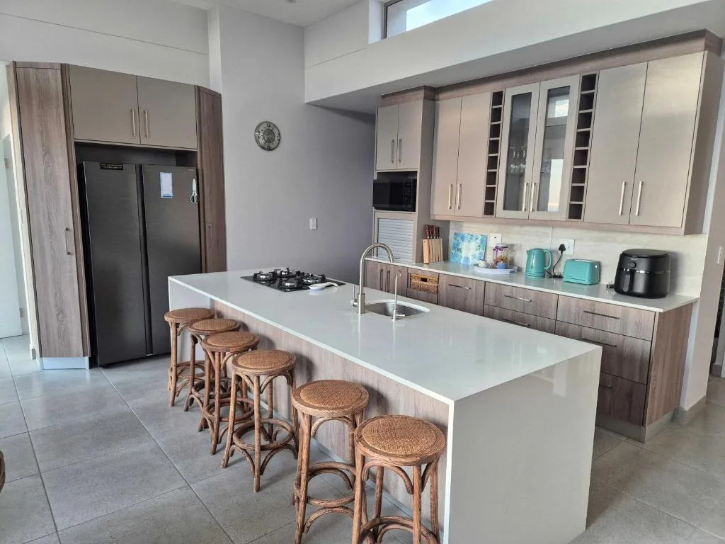 Modern kitchen with white island, gas cooktop, and wooden bar seating