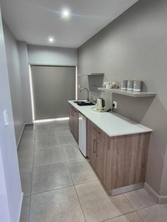 Modern kitchen with wood cabinetry, white countertop, and stainless steel sink