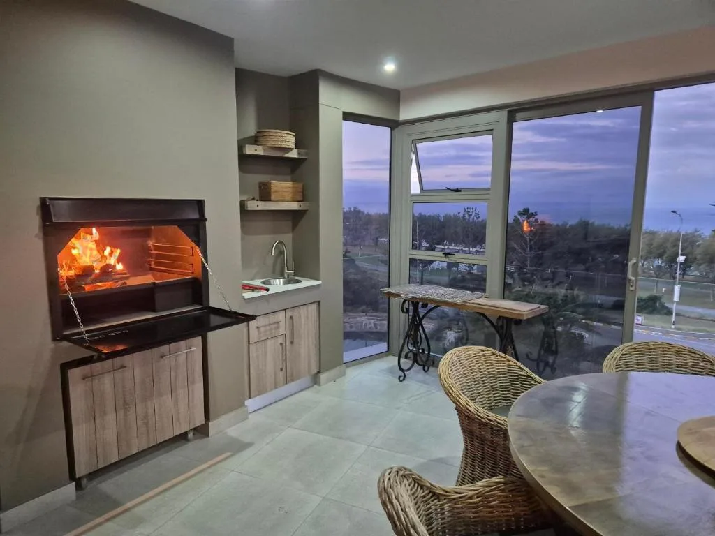 Modern lounge with fireplace, kitchenette, and scenic evening view through large windows