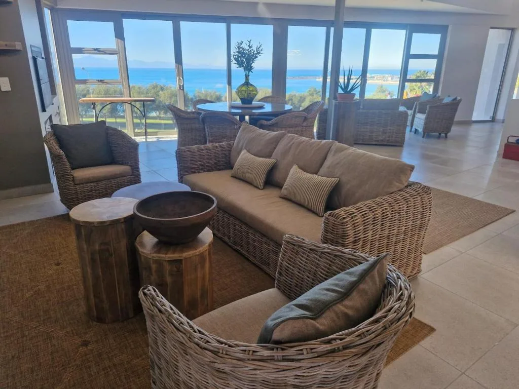 Spacious lounge with wicker furniture and expansive ocean views through floor-to-ceiling windows