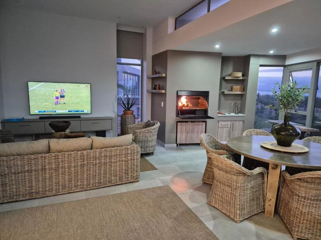 Modern lounge with wicker furniture, fireplace, and TV overlooking lagoon