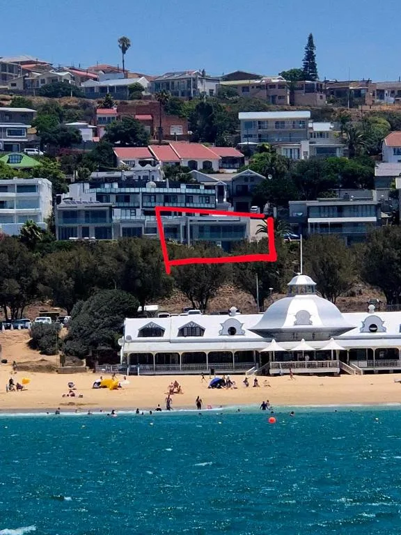 Beachfront villa with ocean, sand, and coastal town hillside backdrop