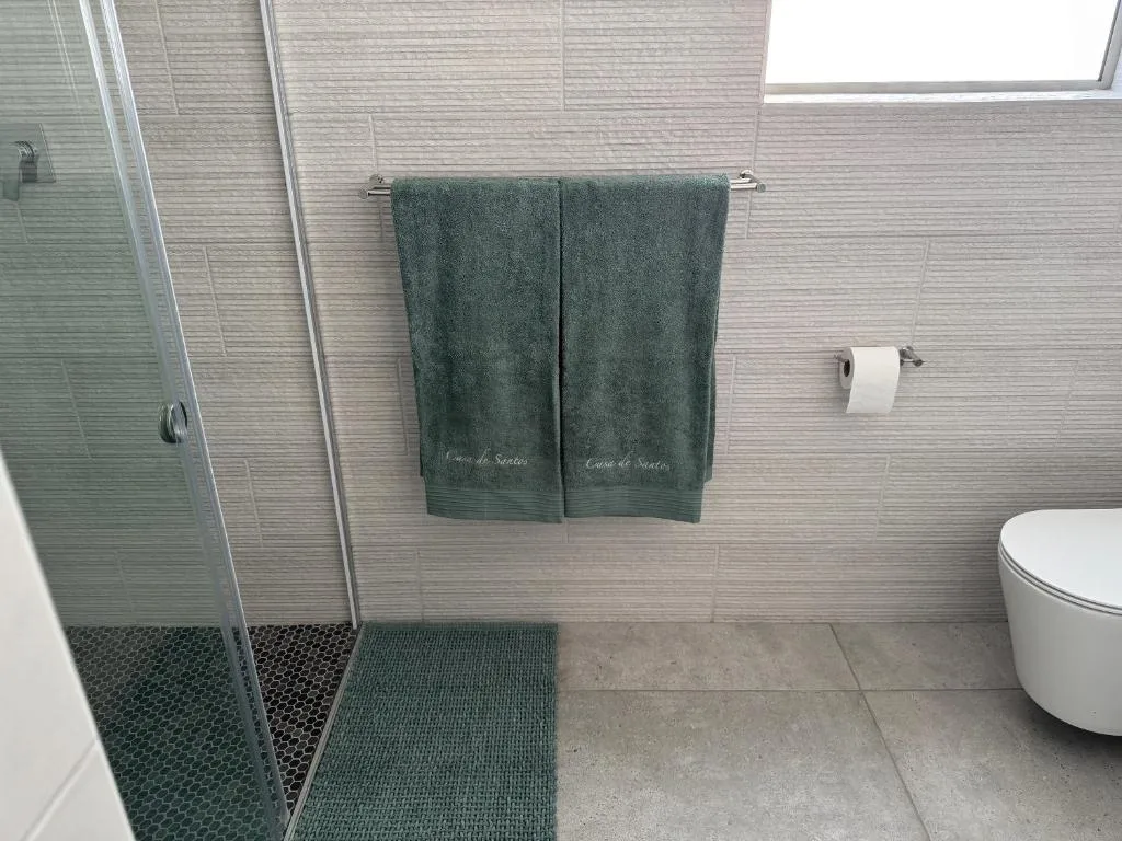 Modern bathroom with walk-in shower, green towels, and white toilet