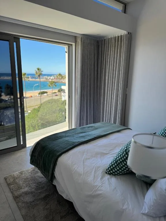 Bright bedroom with coastal view through glass doors and palm trees