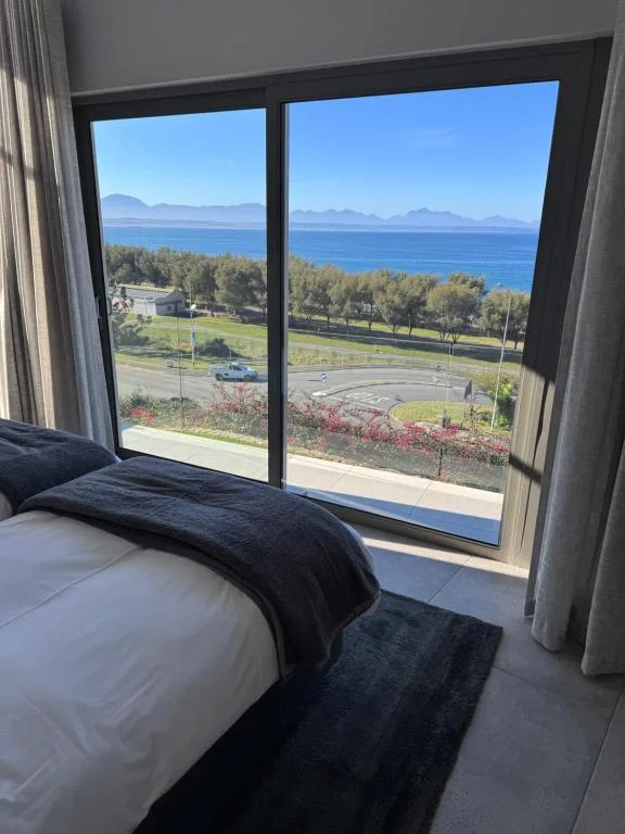 Bedroom with ocean and mountain views through large windows