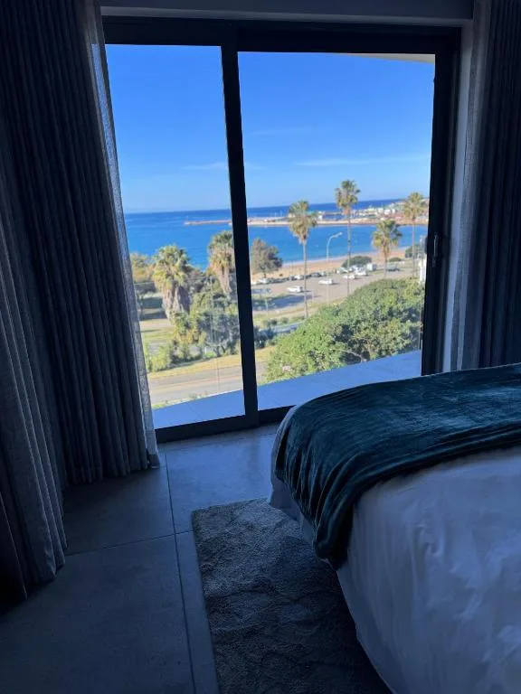 Bedroom with ocean and coastal town views through large windows
