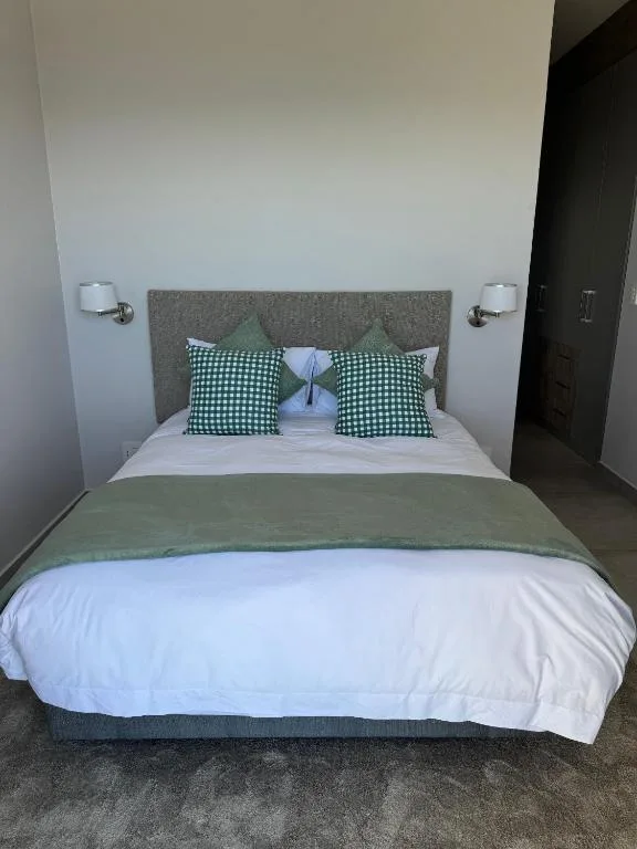 Modern bedroom with grey upholstered headboard and green checkered pillows