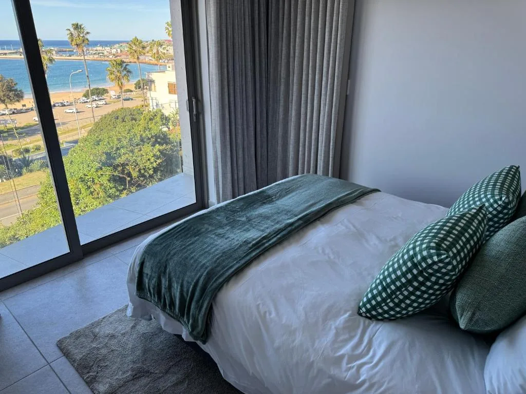 Bedroom with ocean view through large sliding glass doors and coastal scenery