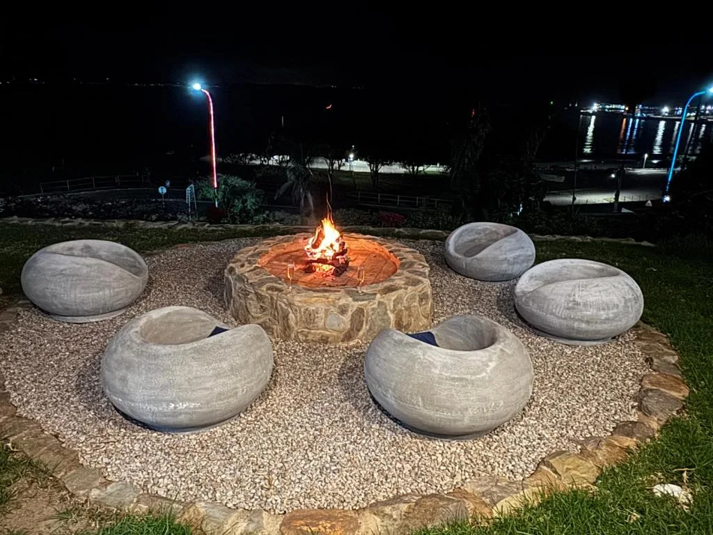 Nighttime fire pit with concrete seating surrounding lit central fireplace