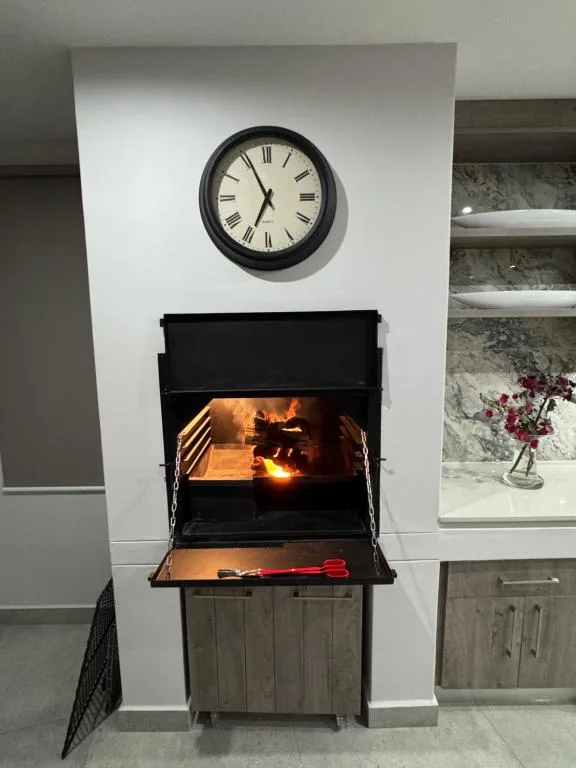 Black wood-burning stove with active fire and wall clock above