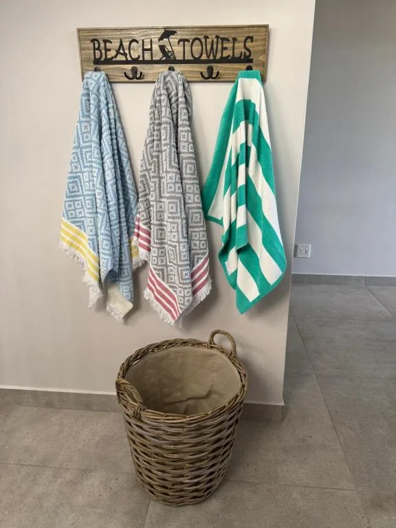 Beach towels hung on rustic wooden rack with wicker basket below