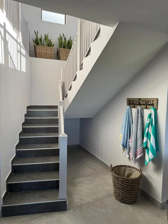 Modern staircase with potted plants and beach towel storage rack